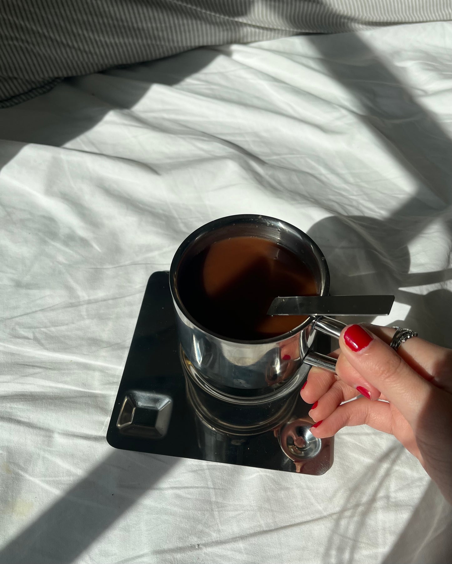 holding a scandi stainless steel coffee mug set (with spoon and plate), drinking morning coffee on bed