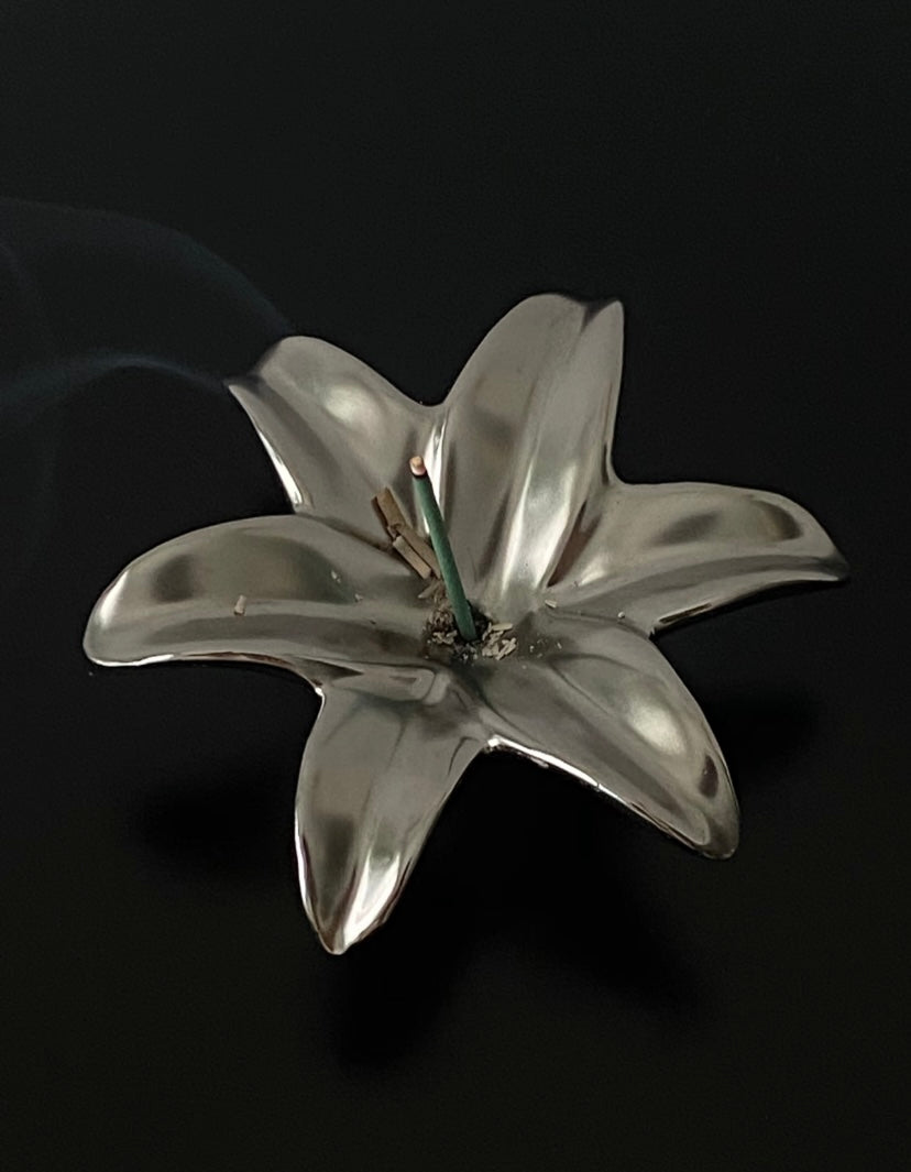 Silver lily flower brooch on a black background