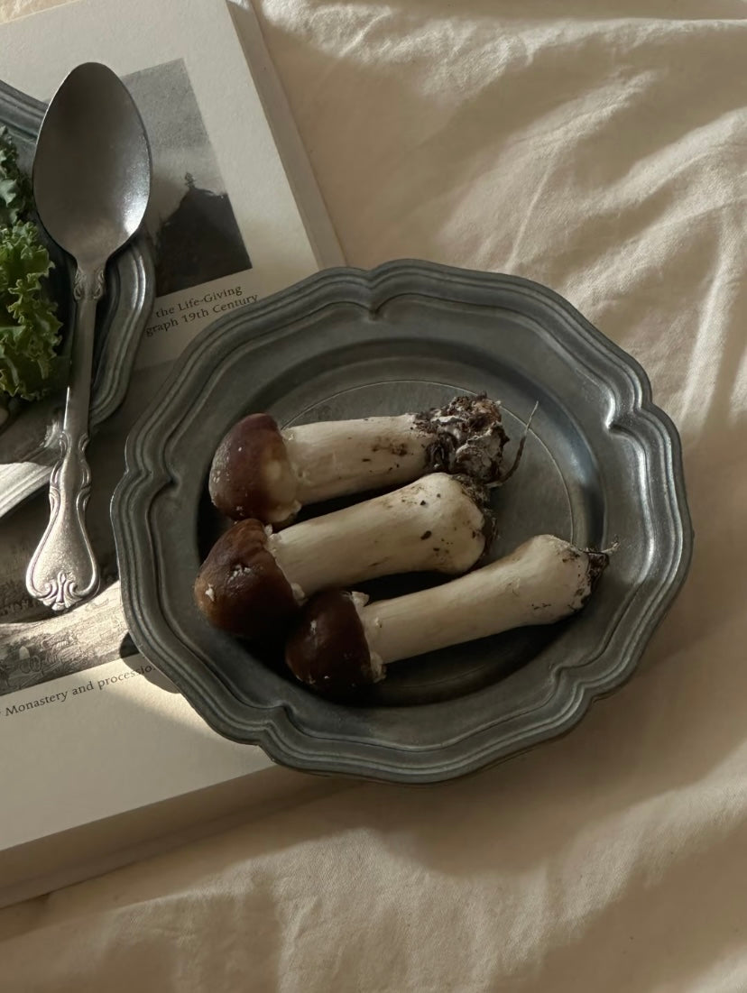 Mushrooms on a gray plate with a spoon and newspaper in the background