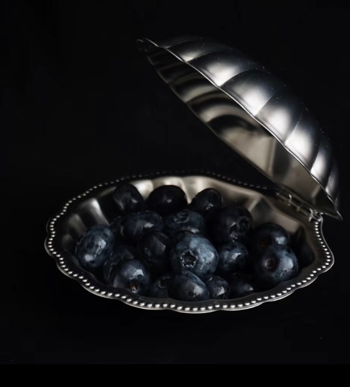 Silver heart-shaped dish filled with blueberries on a black background