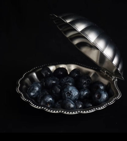 Silver heart-shaped dish filled with blueberries on a black background