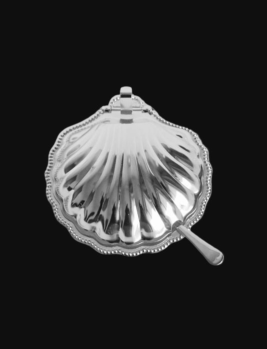 Silver shell-shaped dish with a handle on a light gray background